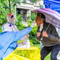 A resident is tested for COVID-19 in the Pudong district of Shanghai on Friday. | AFP-JIJI
