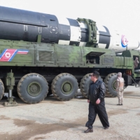 North Korean leader Kim Jong Un walks next to what state media said was a Hwasong-17 intercontinental ballistic missile on its launch vehicle, in this undated photo released on March 25. | KCNA / VIA REUTERS  