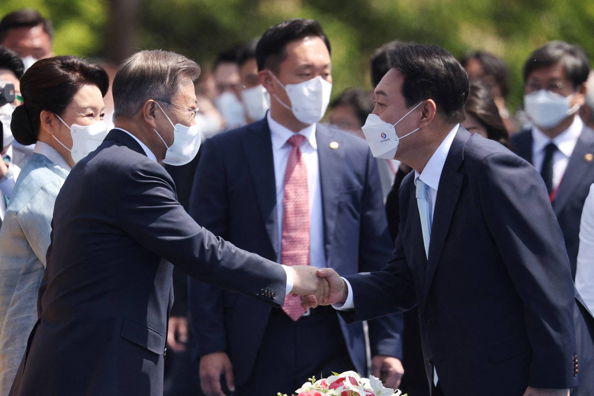 Former South Korean President Moon Jae-in (left) greets new President Yoon Suk-yeol at his inauguration ceremony in Seoul on May 10. | POOL / VIA REUTERS