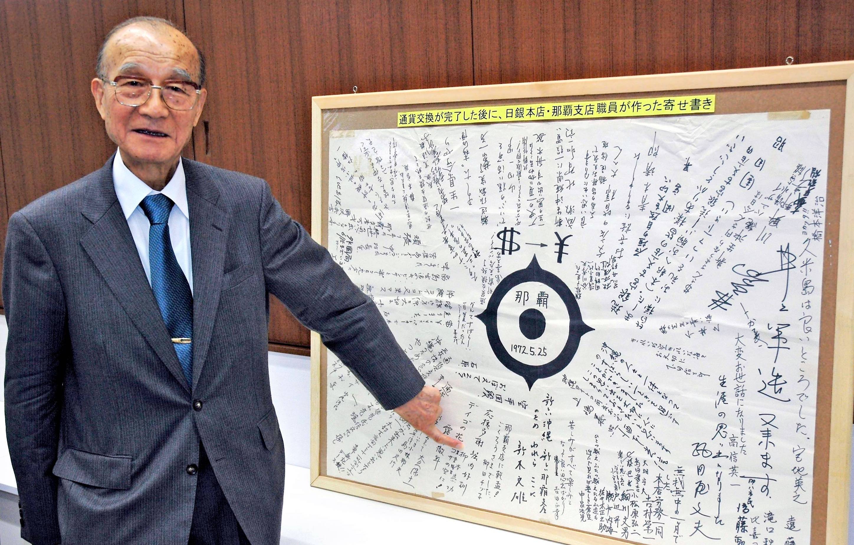 Yoshikuni Horiuchi, then-first deputy manager of the Bank of Japan’s Naha branch, shows messages written by branch staff members in May 1972 when the dollar conversion to the yen was completed, in Naha in May 2012. | THE OKINAWA TIMES