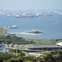 Container ships outside Singapore on Tuesday. The island city has learned from its past experiences of dealing with COVID-19 variants and plans to stay open for business and travel. | BLOOMBERG