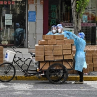 Health care workers deliver supplies to a neighborhood under a COVID-19 lockdown in Shanghai on Wednesday. | AFP-JIJI