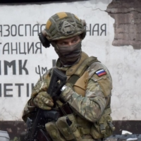 Russian servicemen stand guard at a destroyed factory in Ukraine\'s port city of Mariupol on Wednesday. | AFP-JIJI