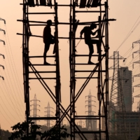 Laborers work next to electricity pylons in Mumbai. The power crunch in India highlights potential challenges for other nations in the region such as Pakistan and Bangladesh with even smaller generation capacities. | REUTERS