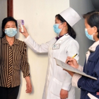 Residents are checked to prevent the spread of the COVID-19 in Pyongyang on Wednesday. A wave of infections, which North Korea first confirmed last week, has fanned worry about a lack of medical resources and vaccines in the isolated country. | KCNA / KNS / VIA AFP-JIJI