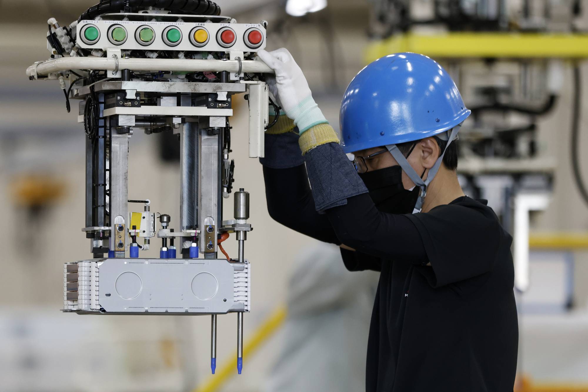 A worker moves a stack of lithium-ion batteries for an electric minivehicle on the production line at Mitsubishi Motors' Mizushima plant in Kurashiki, Okayama Prefecture, on Thursday. | Bloomberg