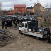 French forensics investigators, who arrived in Ukraine for the investigation of war crimes amid Russia\'s invasion, stand next to a mass grave in the town of Bucha on April 12.  | REUTERS