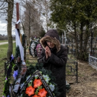 Valentyna Nechyporenko, 77, mourns at the grave of her 47-year-old son Ruslan in Bucha on April 18.  | DANIEL BEREHULAK / THE NEW YORK TIMES