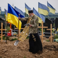 A military chaplain leads a funeral service for Ukrainian servicemen Sergeii Profotilov and Igor Malenkov, both killed in the village of Vilkhivka during the Russian invasion of Ukraine, on Saturday.  | AFP-JIJI