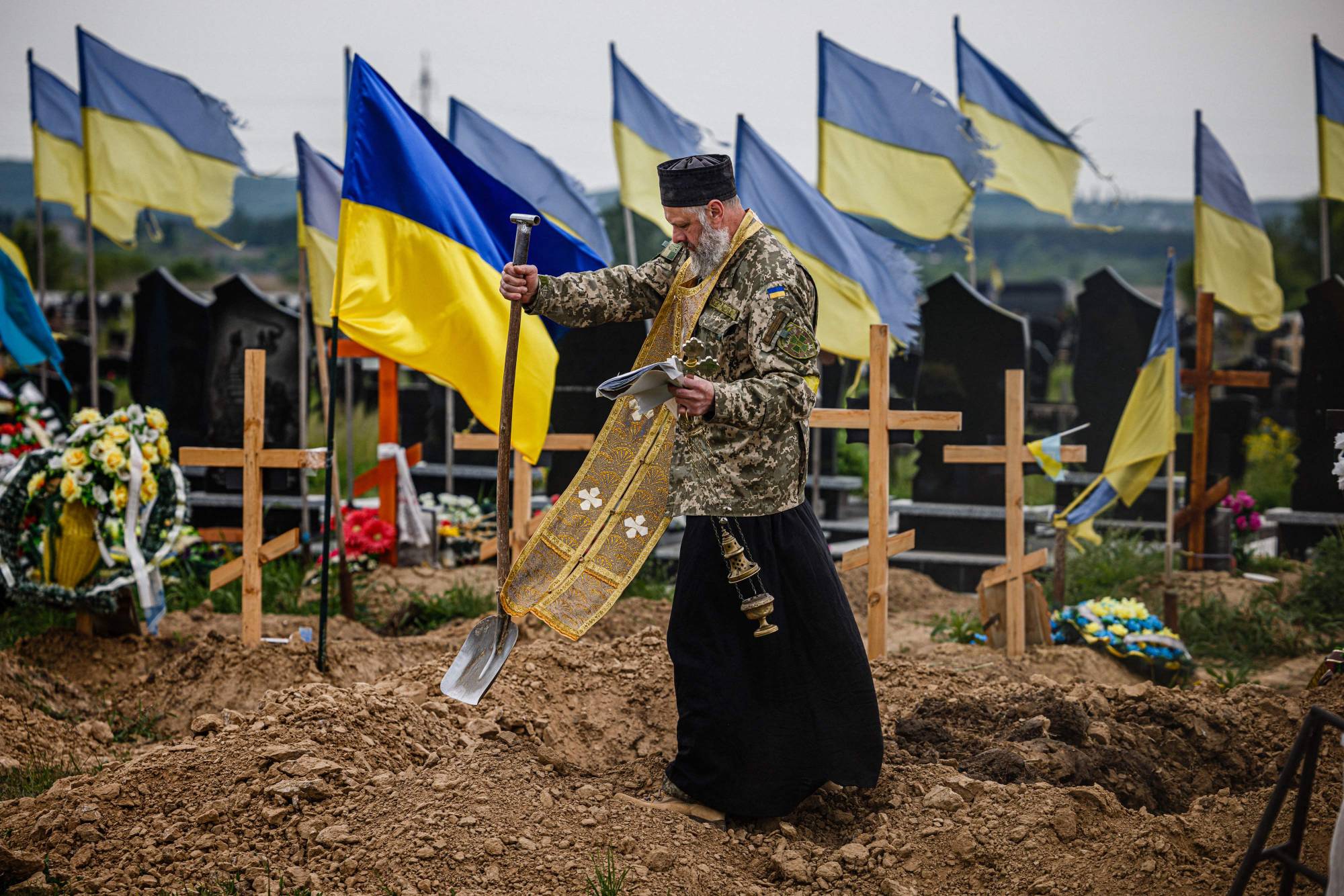 A military chaplain leads a funeral service for Ukrainian servicemen Sergeii Profotilov and Igor Malenkov, both killed in the village of Vilkhivka during the Russian invasion of Ukraine, on Saturday. | AFP-JIJI