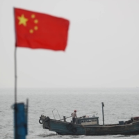 A Chinese flag is seen near a fishing boat off the coast of Qingdao, China. Members of the \"Quad\" alliance plan to use satellite technology to create a tracking system for illegal fishing from the Indian Ocean to the South Pacific by connecting surveillance centers in Singapore and India. | REUTERS