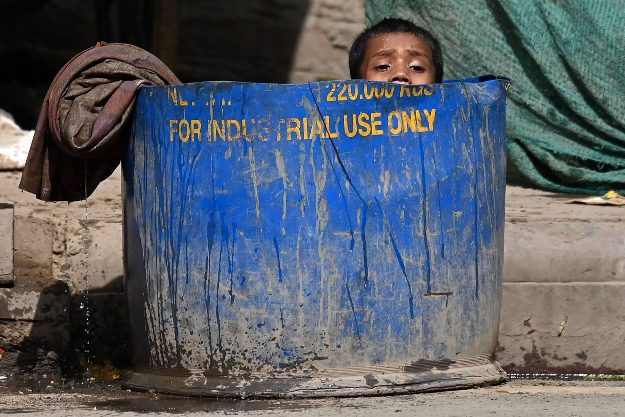 A boy cools off while sitting in a water tub along the roadside on a hot summer day in New Delhi on Sunday.  | AFP-JIJI