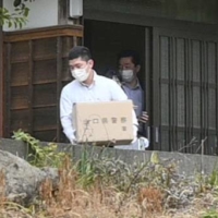 Yamaguchi Prefectural Police investigators carry items from the house of a man who was mistakenly transferred ¥46.3 million by the local government, in Abu, Yamaguchi Prefecture, on Friday. | KYODO
