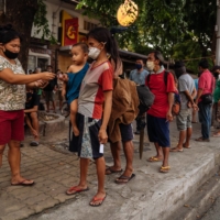 Filipinos line up for food in Metro Manila, a dense patchwork of 16 cities that make up the Philippines\' urban core | HANNAH REYES MORALES / THE NEW YORK TIMES