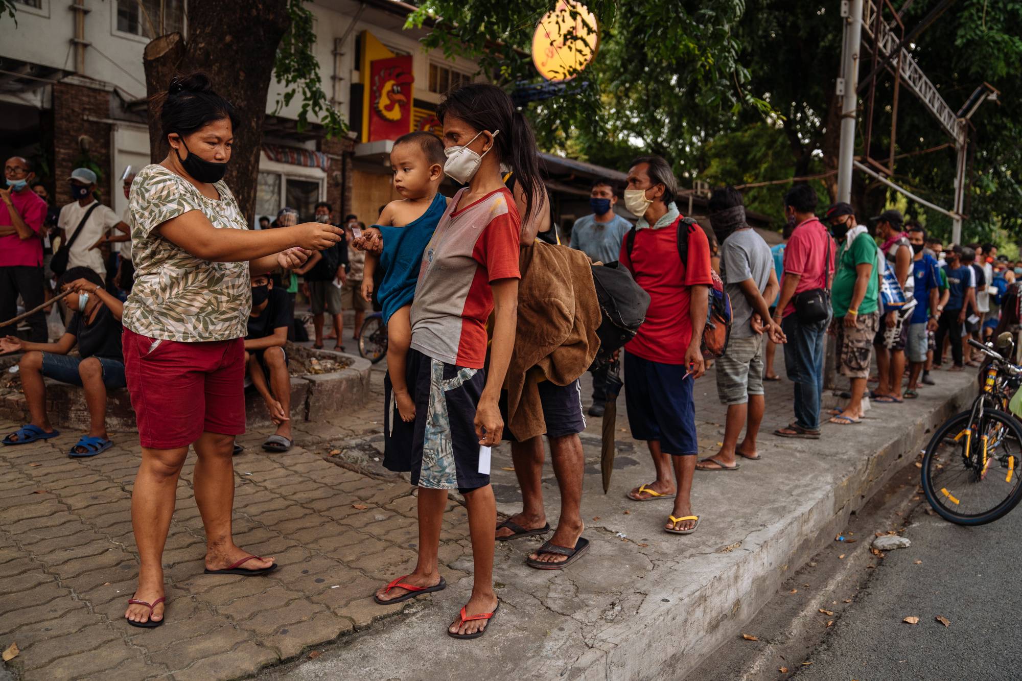 Filipinos line up for food in Metro Manila, a dense patchwork of 16 cities that make up the Philippines' urban core | Hannah Reyes Morales / The New York Times