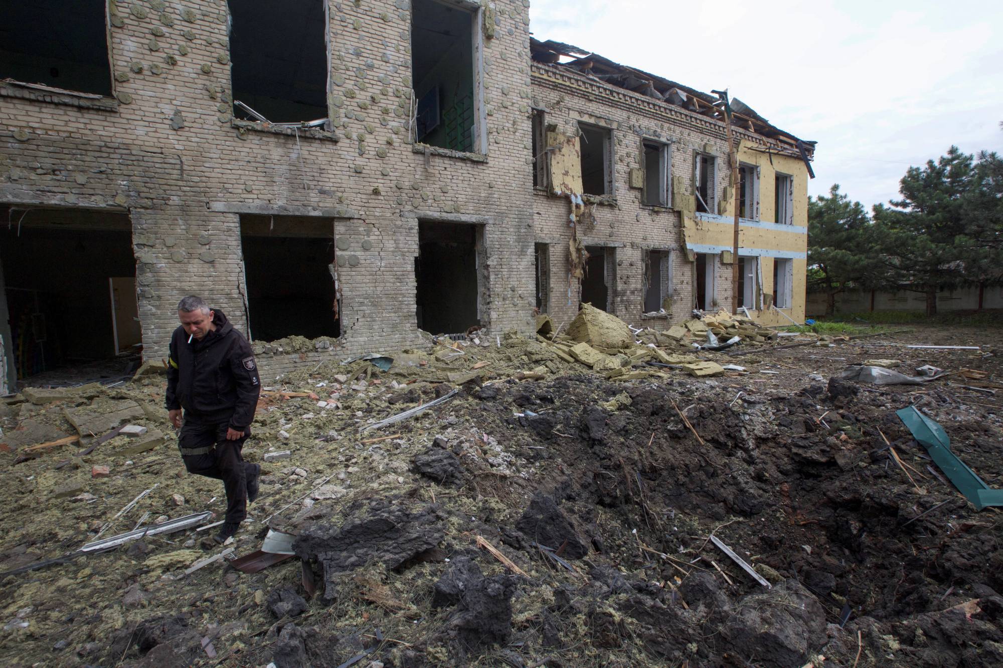 A police officer walks next to a school building damaged by a Russian military strike in the settlement of Kostiantynivka, in Donetsk region, Ukraine, on Sunday. | REUTERS