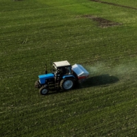 A tractor spreads fertilizer on a wheat field near the village of Yakovlivka after it was hit by an aerial bombardment outside Kharkiv, Ukraine, on April 5. | REUTERS
