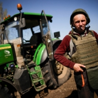 A Ukrainian farmer, wearing body armor and a helmet, works at the topsoil in a field in the Zaporizhzhia region of Ukraine on April 26. | REUTERS