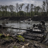 A Ukrainian soldier tries to salvage a heavy machine gun from an abandoned Russian tank in the Seversky Donets River near Sievierodonetsk, Ukraine, on Wednesday. The failed river crossing that took place at this spot over several days in early May was one of the most lethal engagements of the war for the Russian army.  | IVOR PRICKETT / THE NEW YORK TIMES