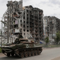 Service members of pro-Russian troops drive an armored vehicle in the town of Popasna in the Luhansk Region of Ukraine on Thursday. | REUTERS