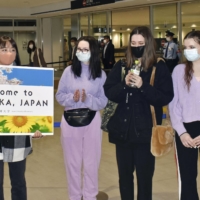 Ukrainian students are welcomed at an airport in Fukuoka Prefecture on March 25. | KYODO