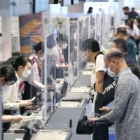 People line up at check-in counters for international flights at Haneda Airport in April. | KYODO