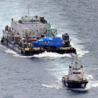 A sunken tour boat covered with a blue tarpaulin is transported to the port of Abashiri, Hokkaido, on Friday after being salvaged the previous day. | KYODO