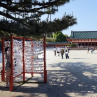 A tourist ties fortune paper to a rope at Yasaka shrine in Kyoto on May 3 during the Golden Week holidays. | BLOOMBERG