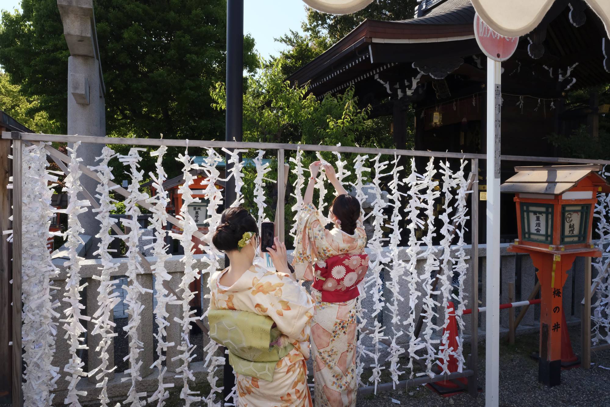 A tourist wearing a kimono ties fortune paper to a rope at Yasaka shrine in Kyoto on May 3. It will likely take awhile for the tourism sector to achieve a full recovery, as the timing of the full reopening of the border remains uncertain. | Bloomberg