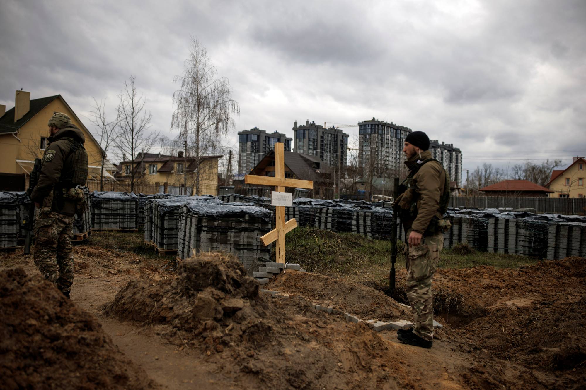 Ukrainian soldiers stand next to the grave of a civilian in the city of Bucha, Ukraine, who according to residents was killed by Russian soldiers during their occupation of the area, on April 6.  | REUTERS