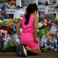 A girl pays respects at the memorial at Robb Elementary school where a gunman recently killed 19 children and two adults, in Uvalde, Texas, on Saturday. | REUTERS