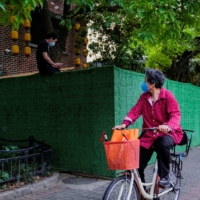 A cyclist notices a resident sitting on a barrier at a closed residential area during a COVID-19 lockdown in Shanghai on Monday. | REUTERS