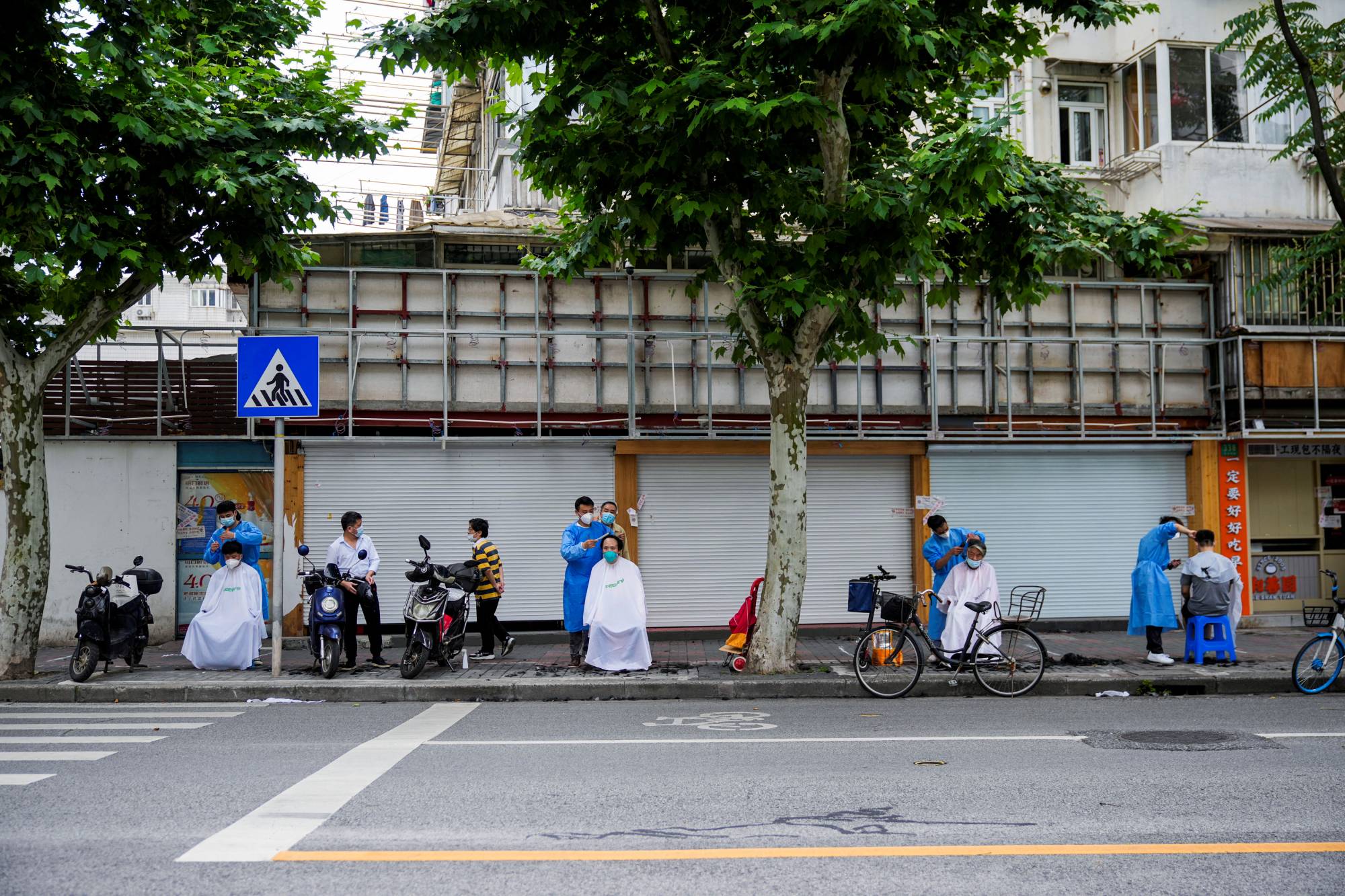 Residents get haircuts on a street in Shanghai on Monday. | REUTERS