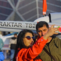 People pose for a picture in front of a Bayraktar TB2 unmanned combat aerial vehicle at Teknofest aerospace and technology festival in Baku, Azerbaijan on Friday. | REUTERS