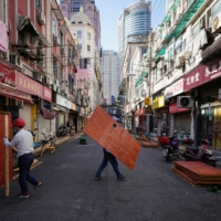 Workers dismantle barriers in a residential area of Shanghai on Tuesday.  | REUTERS 