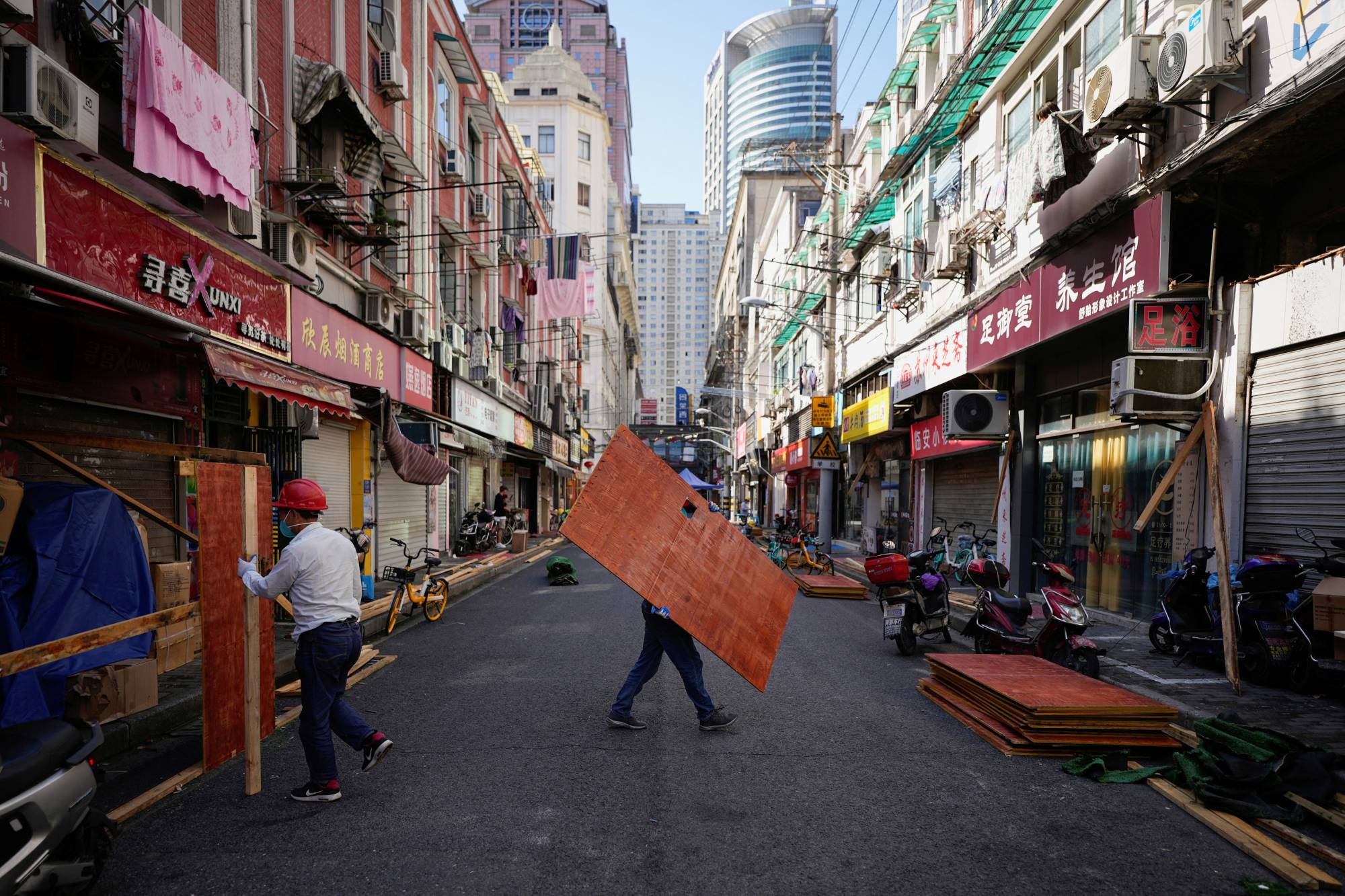 Workers dismantle barriers in a residential area of Shanghai on Tuesday.  | REUTERS 