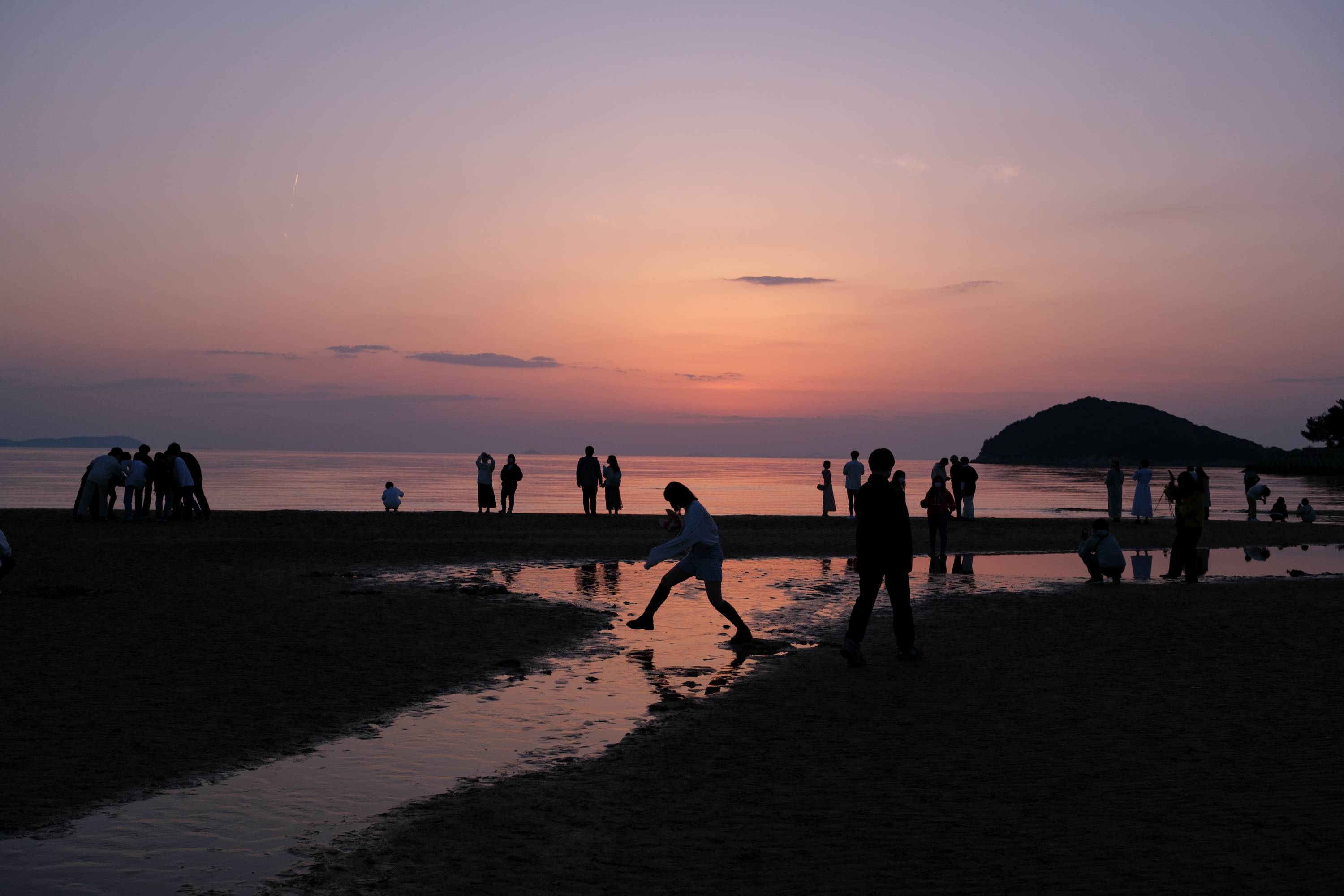 Locals and visiting college students enjoy the mirrored sunset at Chichibugahama Beach in Mitoyo. The beach went viral on Instagram and now draws daytrippers from around the region. | LANCE HENDERSTEIN