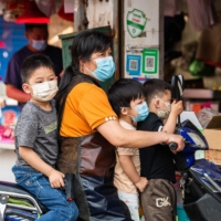 A local resident rides a scooter with three childen at a market in Shanghai\'s Pudong district Tuesday, ahead of the lifting of a COVID-19 lockdown in the city. | AFP-JIJI