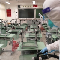 Workers in protective suits disinfect a classroom at a school to prepare for the resumption of classes in Shanghai on Monday.  | CNSPHOTO / VIA REUTERS