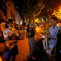 People drink on a street in Shanghai on Tuesday as the city prepares to end the lockdown placed to curb the COVID-19 outbreak. | REUTERS