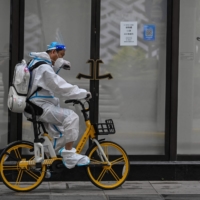 A worker rides a bicycle on a street in the Jing\'an district of Shanghai on Wednesday, after the end of a heavy-handed COVID-19 lockdown that lasted two months. | AFP-JIJI