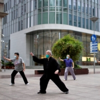 People wearing face masks practice Tai Chi on a shopping street in Shanghai on Wednesday, after the lifting of a COVID-19 lockdown. | REUTERS