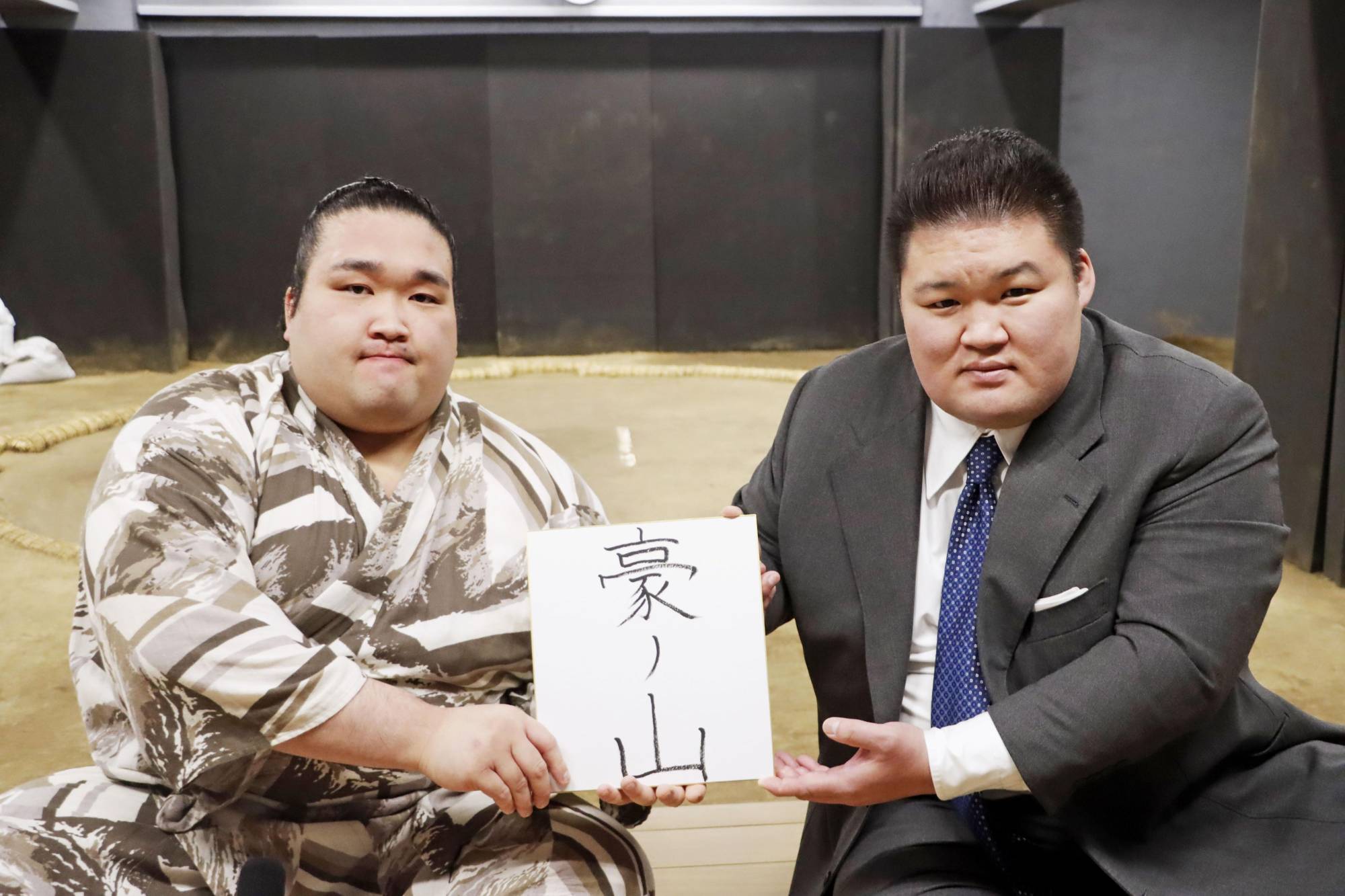 Newly promoted jūryō wrestler Nishikawa (left) presents his new ring name, Gonoyama, alongside Takekuma stablemaster (ex-ozeki Goeido) at Takekuma stable in Tokyo's Ota ward on May 25. | JAPAN SUMO ASSOCIATION