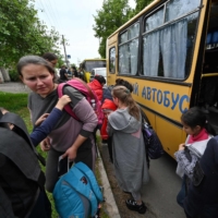 Evacuees exit a bus as they arrive in a small town east of Kharkiv, Ukraine, on Monday. | AFP-JIJI