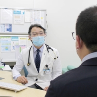Fumio Otsuka, deputy director of Okayama University Hospital, speaks with a patient at the facility\'s COVID-19 aftercare clinic. | OKAYAMA UNIVERSITY HOSPITAL
