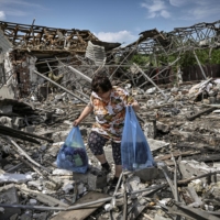 A woman collects belongings in the ruble of their house after a strike destroyed three houses in the city of Slovyansk, Ukraine on Wednesday. | AFP-JIJI