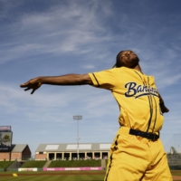 Maceo Harrison, a hip-hop dancer and teacher who never played baseball, serves as the Savannah Bananas first-base coach during a game in Kansas City, May 7, 2022. Dancing first-base coaches have become an especially beloved tradition for the Bananas, a collegiate summer league team has amassed a big following by leaning into entertainment | SHAWN BRACKBILL / THE NEW YORK TIMES

