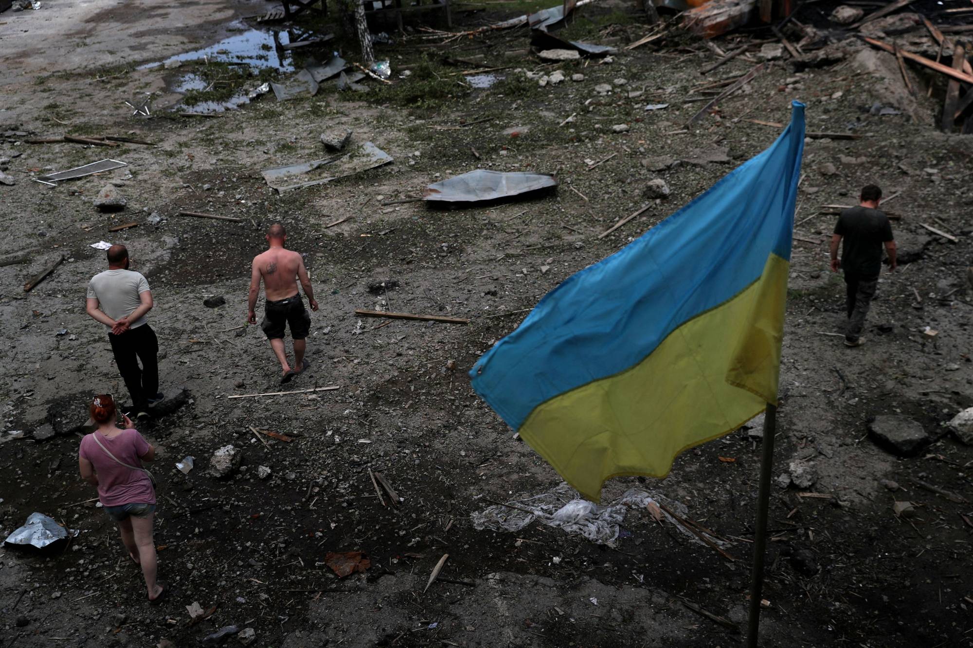 Employees inspect their workplace, a damaged wood warehouse, after an attack amid Russia's invasion of Ukraine, in the outskirts of Kharkiv on Friday. | REUTERS