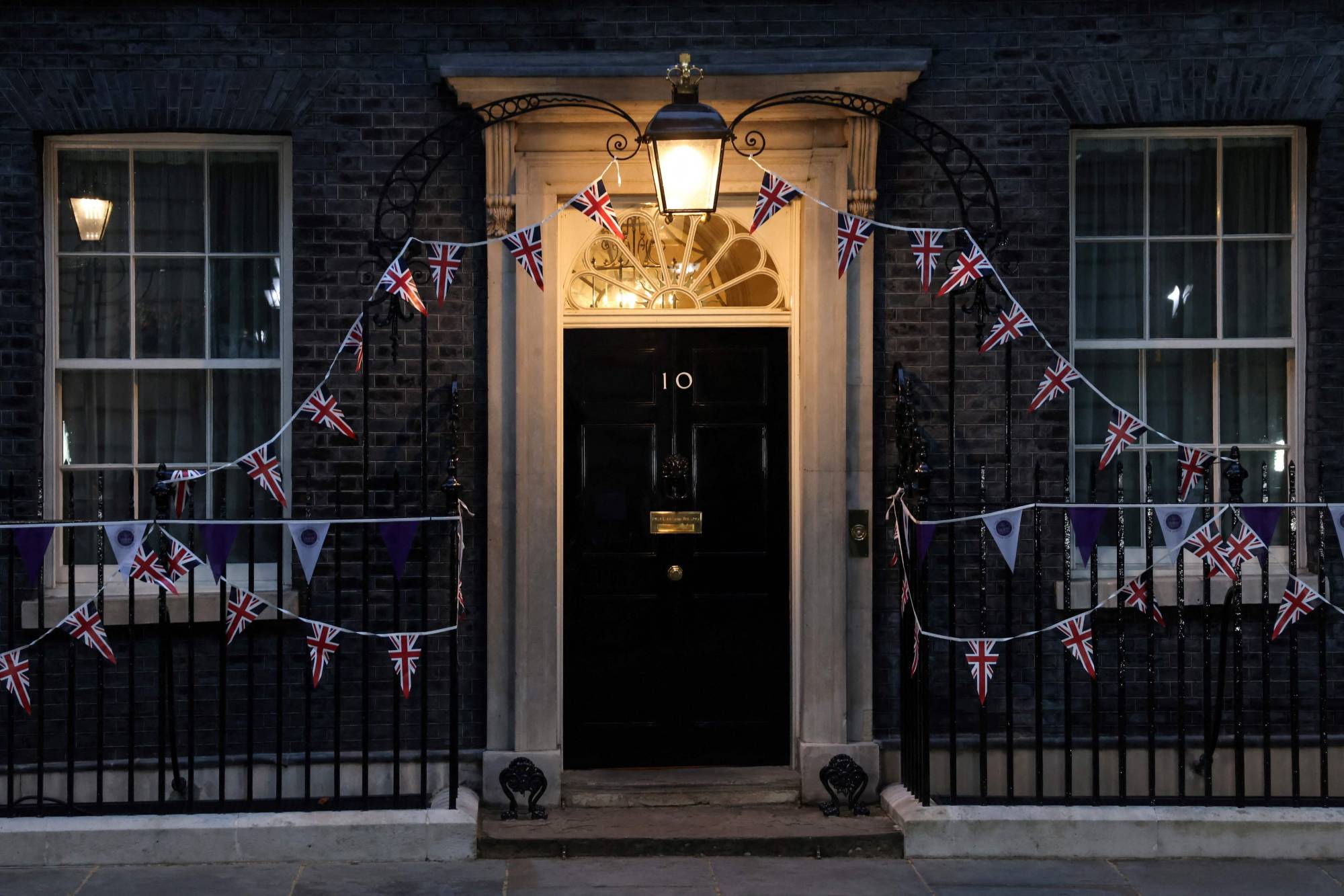 The entrance to No. 10 Downing St. is illuminated Monday evening. Johnson's hollow victory over the rebels leaves the British prime minister weakened and exposed the divisions that may ultimately sink his premiership. | AFP-JIJI
