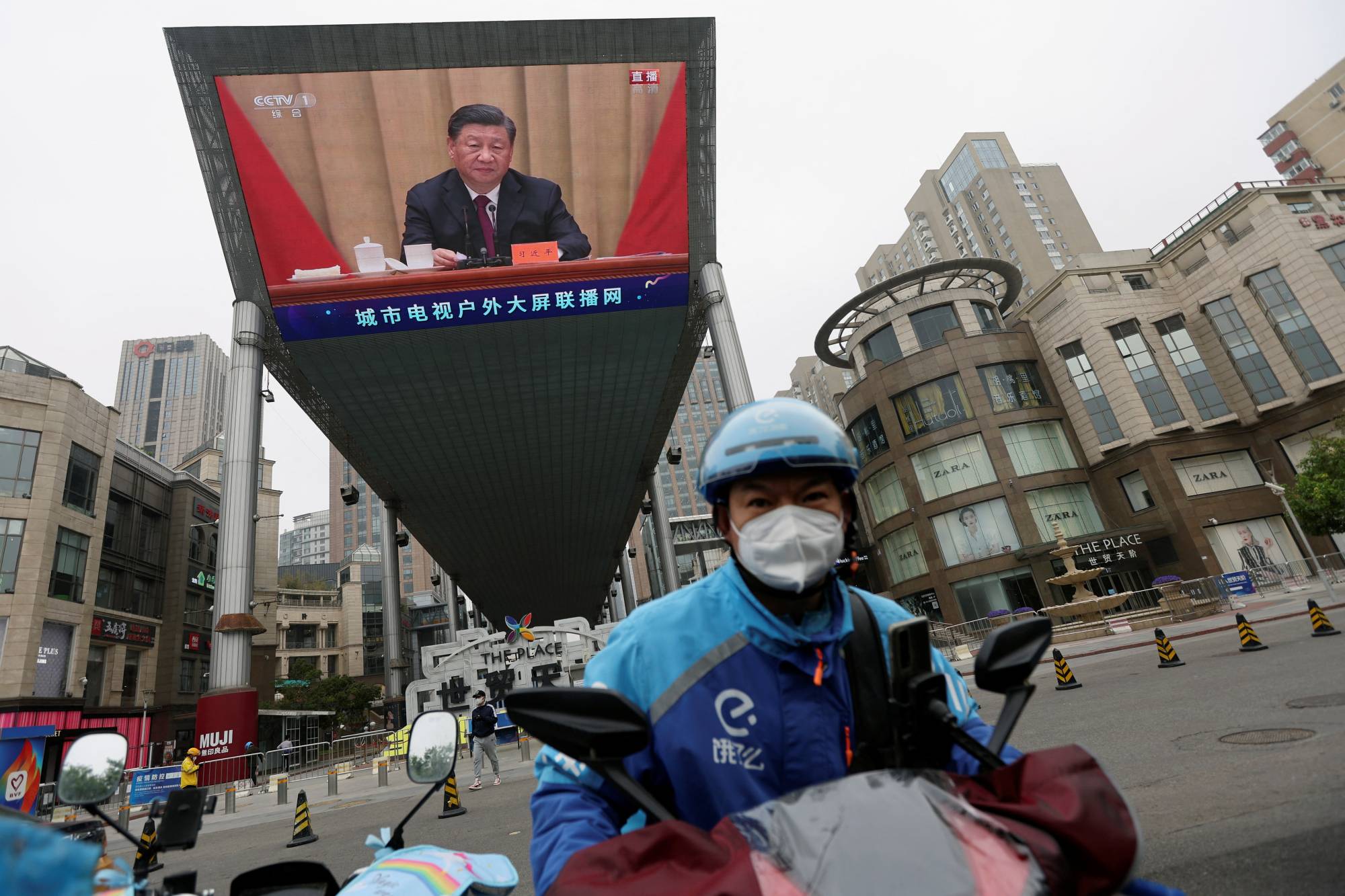 A delivery worker rides near a giant screen showing Chinese President Xi Jinping at an event celebrating the 100th anniversary of the founding of the Chinese Communist Youth League in Beijing, in May. | REUTERS